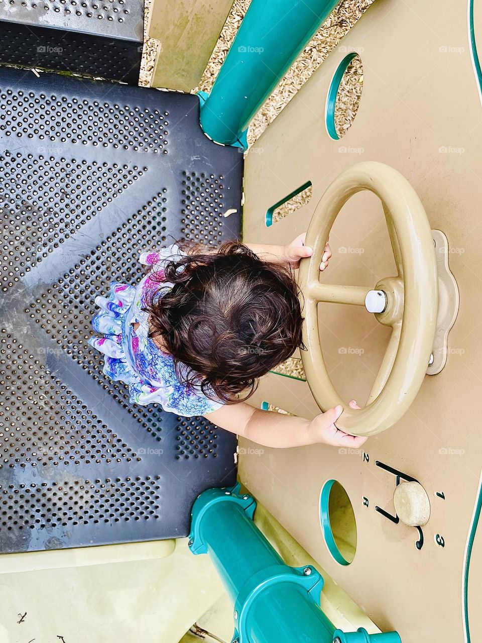 Toddler girl at the park playing with steering wheel, baby driving, toddler playing on a playground at a park