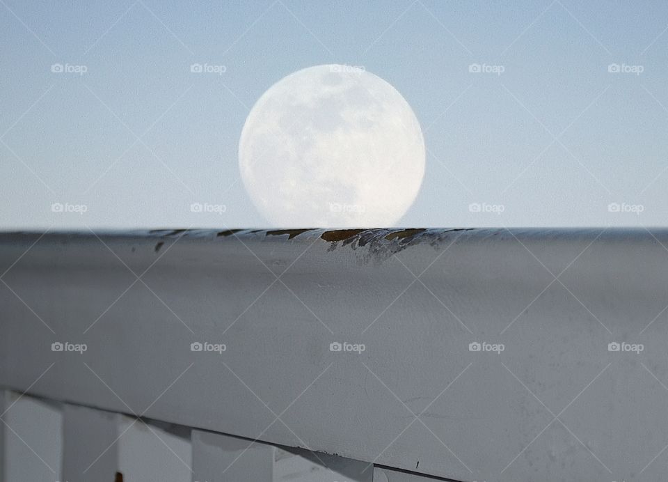 Full Moon peaking over a railing as it rises over Lake Michigan