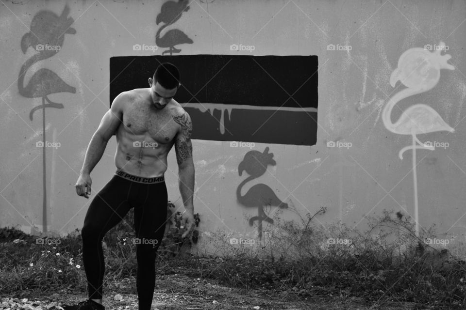 Shirtless man standing near wall