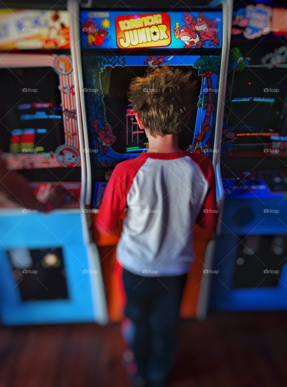 1980s Videogame Arcade. Boy Playing Vintage Videogames In A 1980s Arcade
