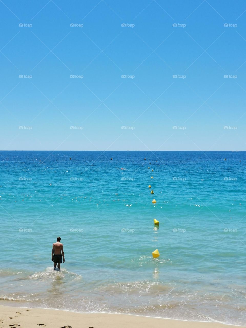 Sunny summer day. A man goes into the sea to swim. Beautiful blue sky and water. Amazing sunny weather. Holiday time. Enjoy the moment...