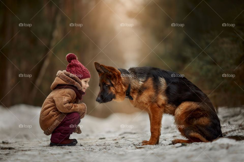 Little girl with German shepherd 6-th months puppy at early spring forest