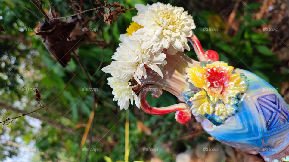 Beautiful white flowers in a colourful flowerpot with a flower sculpture