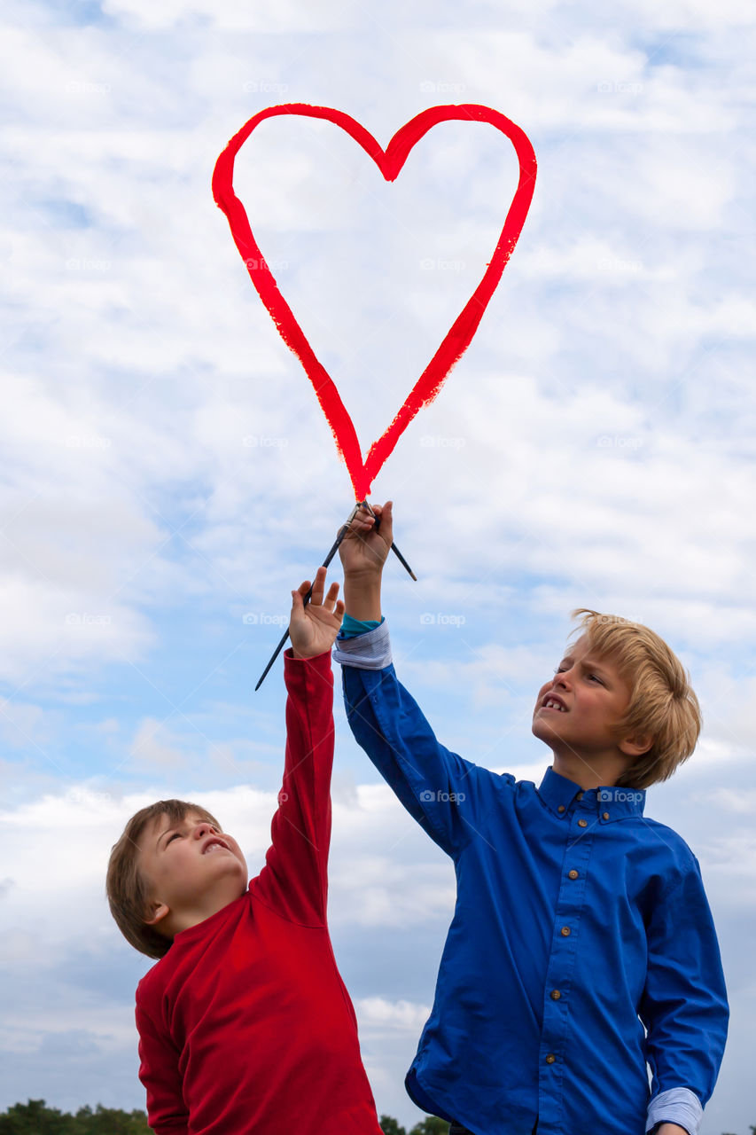 Two children making heart shape with paint brush