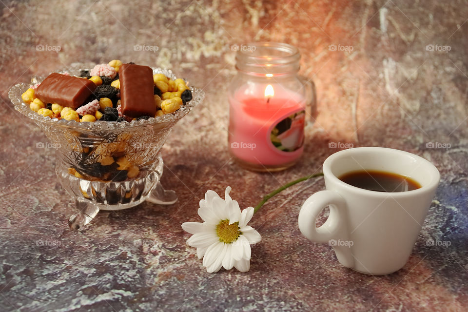 Morning coffee in a hurry a cup of coffee, flowers in a vase, dried fruits and sweets in a vase, a burning candle