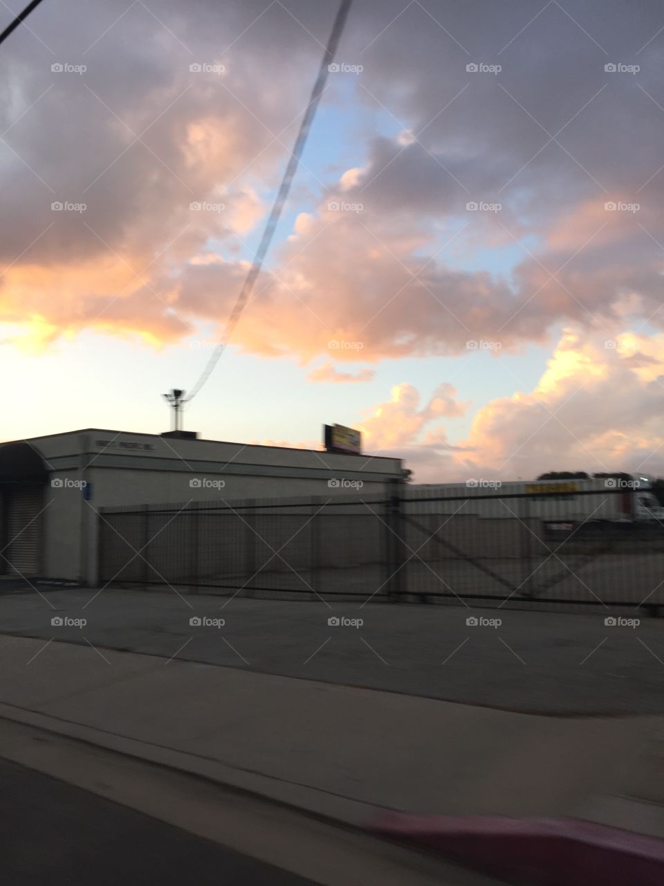 Sunset with concrete building and road. Clouds with blue sky and sunlight. 