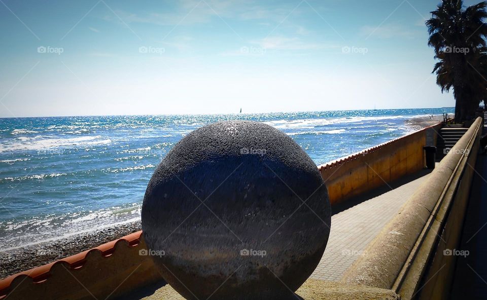 On top of the concrete sphere there is a sailboat