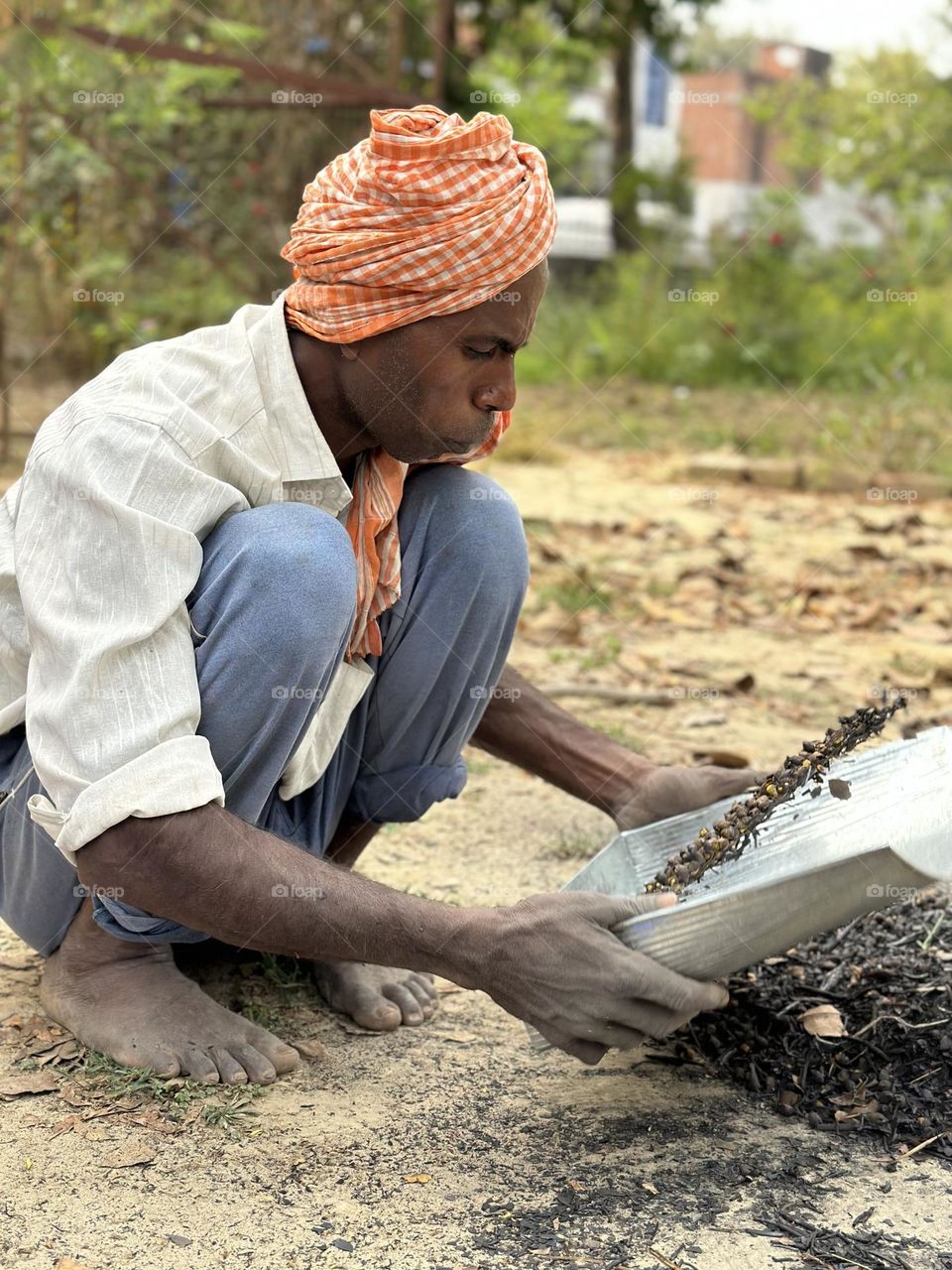 Indian man using a utensil called soup for extraction of roasted nuts