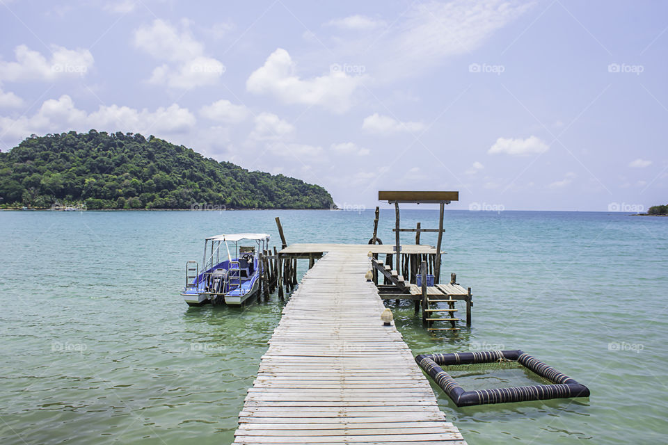 Speed boats moored at the wooden bridge and blue sky in the sea.