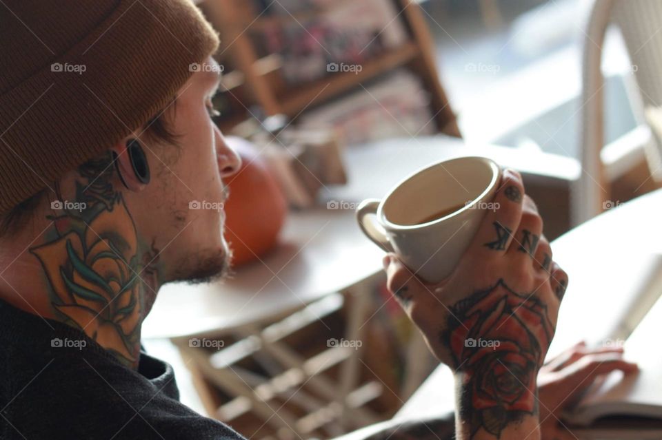 Side view of a tattooed man drinking coffee