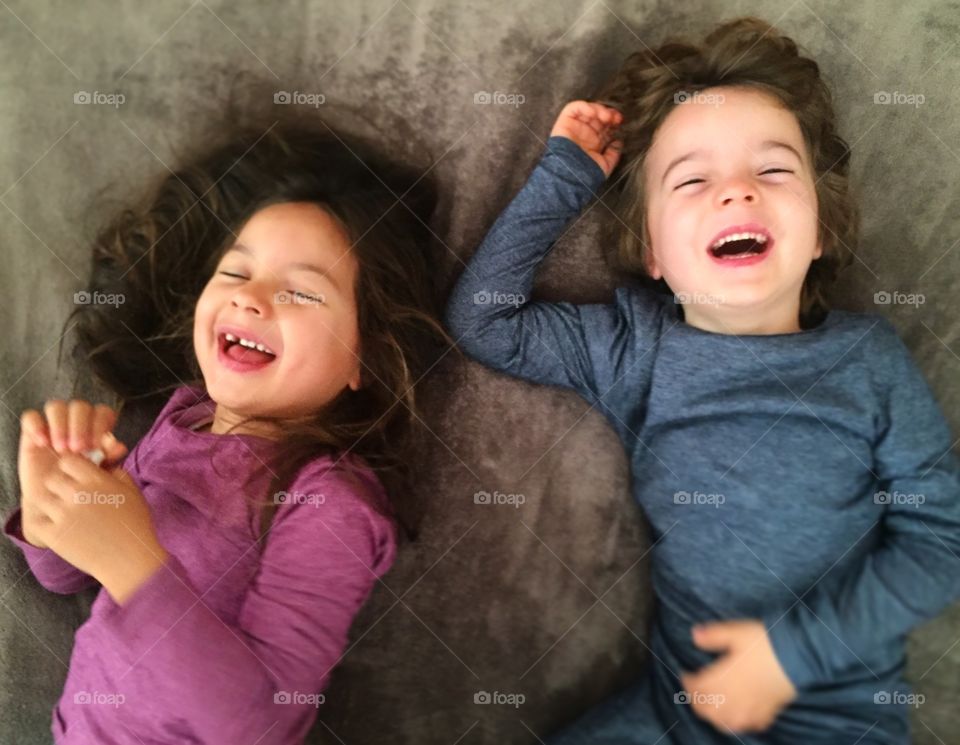 Elevated view of happy sibling lying on bed