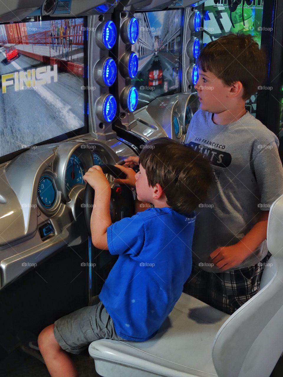 Young Boys Playing Videogames. Two Young Brothers Playing A Driving Videogame
