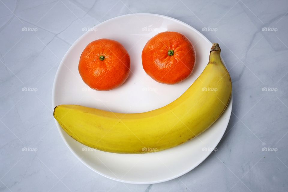 Ripe tangerines and banana fruits on a plate