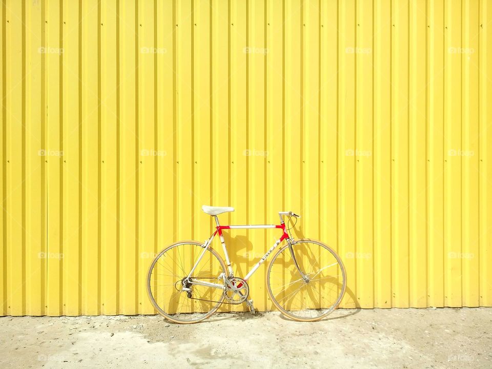 a bicycle stand ahead of yellow wall