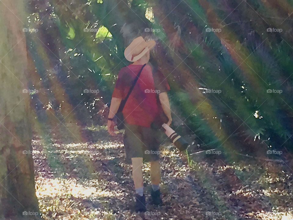 Man on a hot summer day in the woodland walking in the rainbow of the sun’s rays.