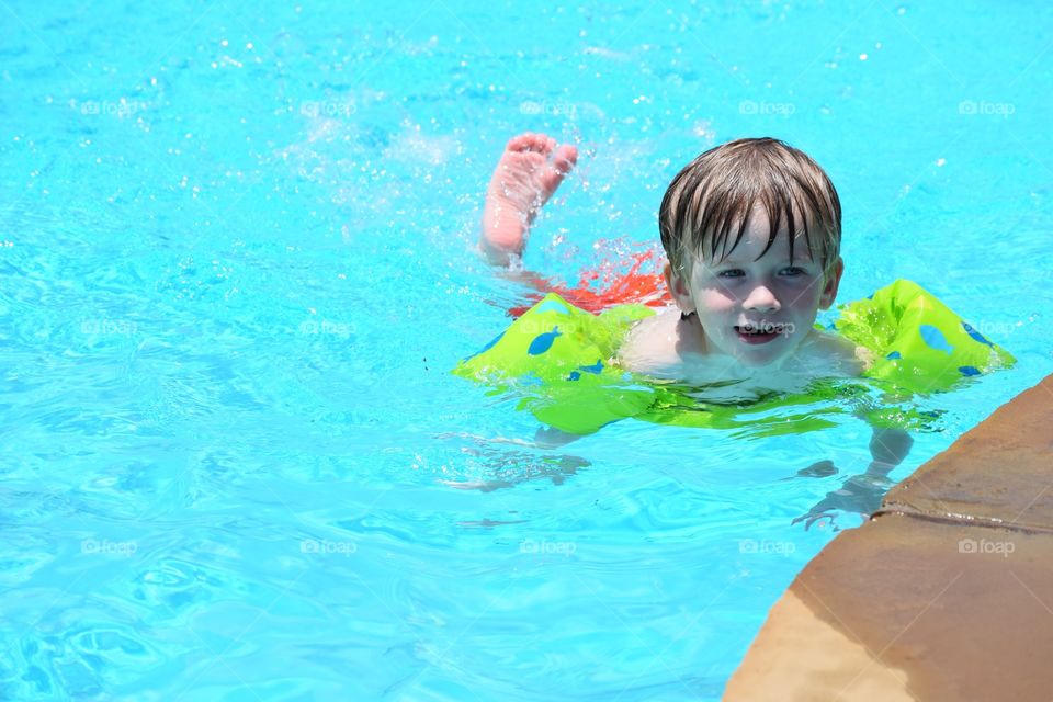 Little boy swimming in pool at home