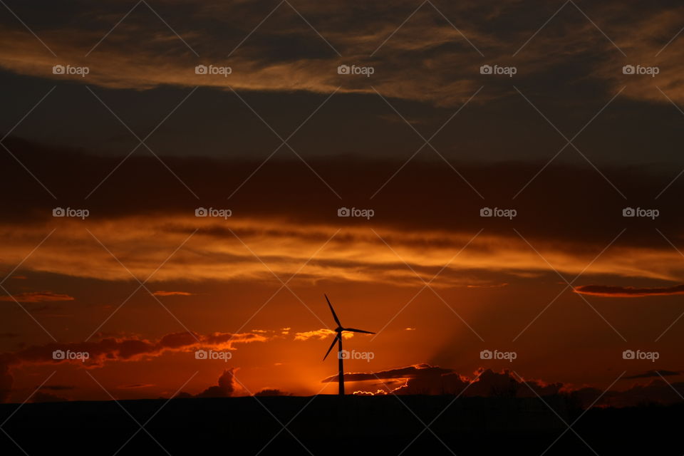 Wind turbine on the horizon at sunset. Salento, Puglia, Italy.
