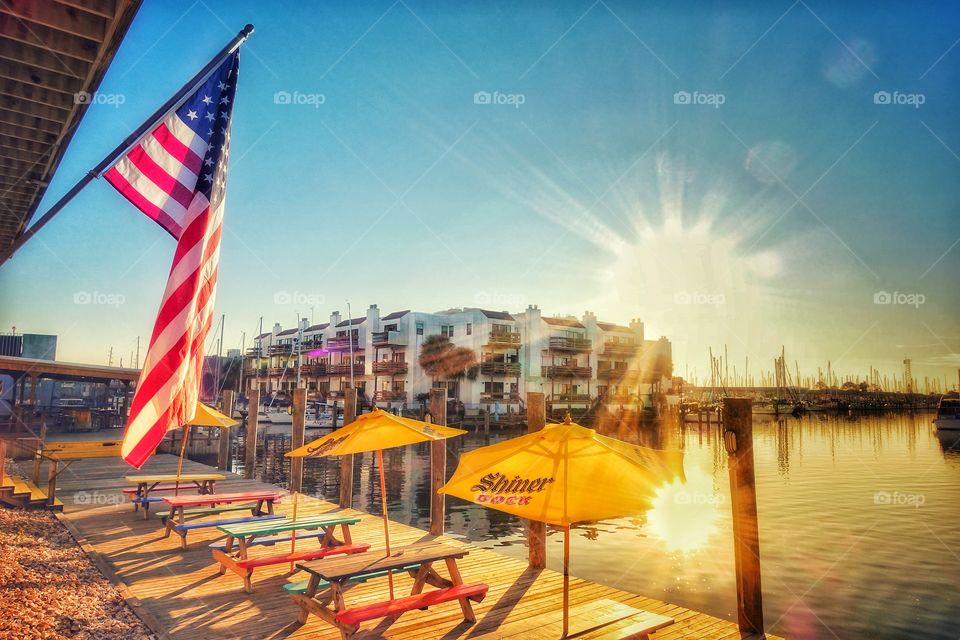 Sunset view outside a restaurant along Lake Pontchartrain, New Orleans, USA. Image features a flag of the United States of America.
