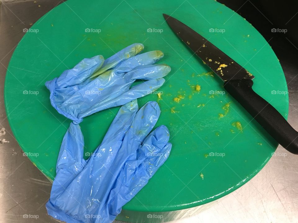 Unwashed chopping board with blue gloves 