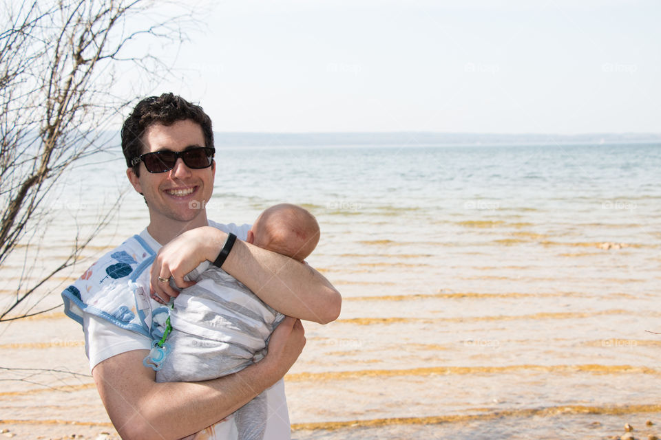 Young man carrying his baby near the sea