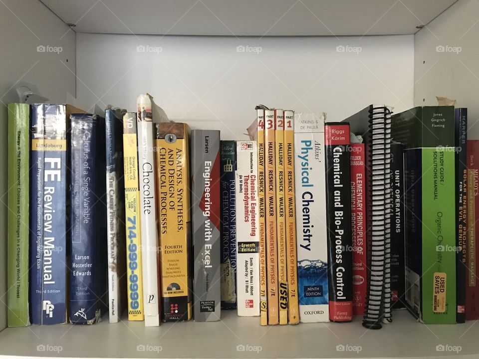 A mixture of science and engineering text books on a white shelf