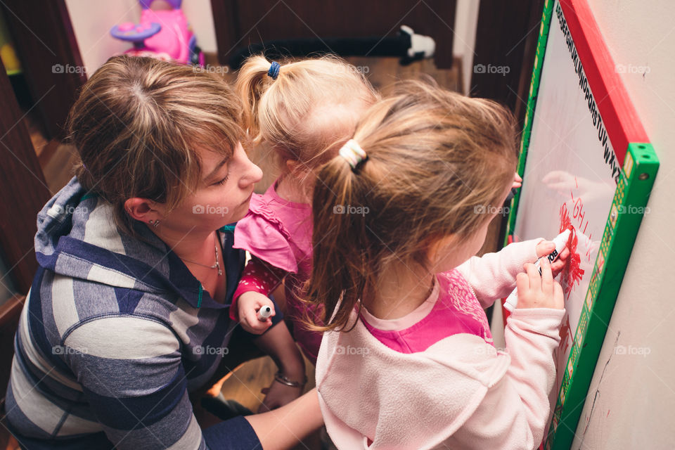 Children drawing a pictures learning a letters playing together using whiteboard and markers