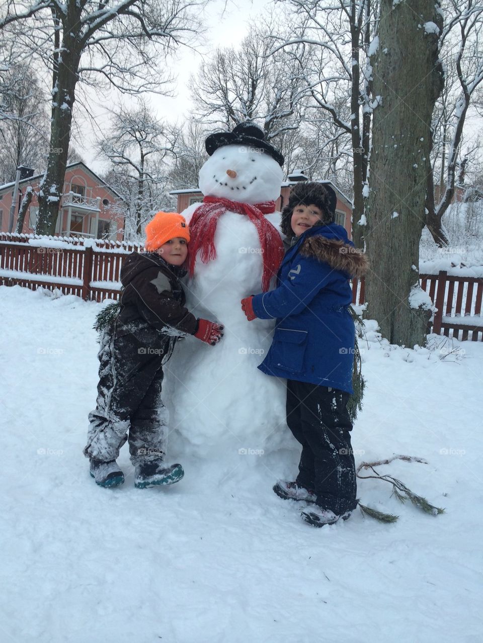 Two boys hugging snowman
