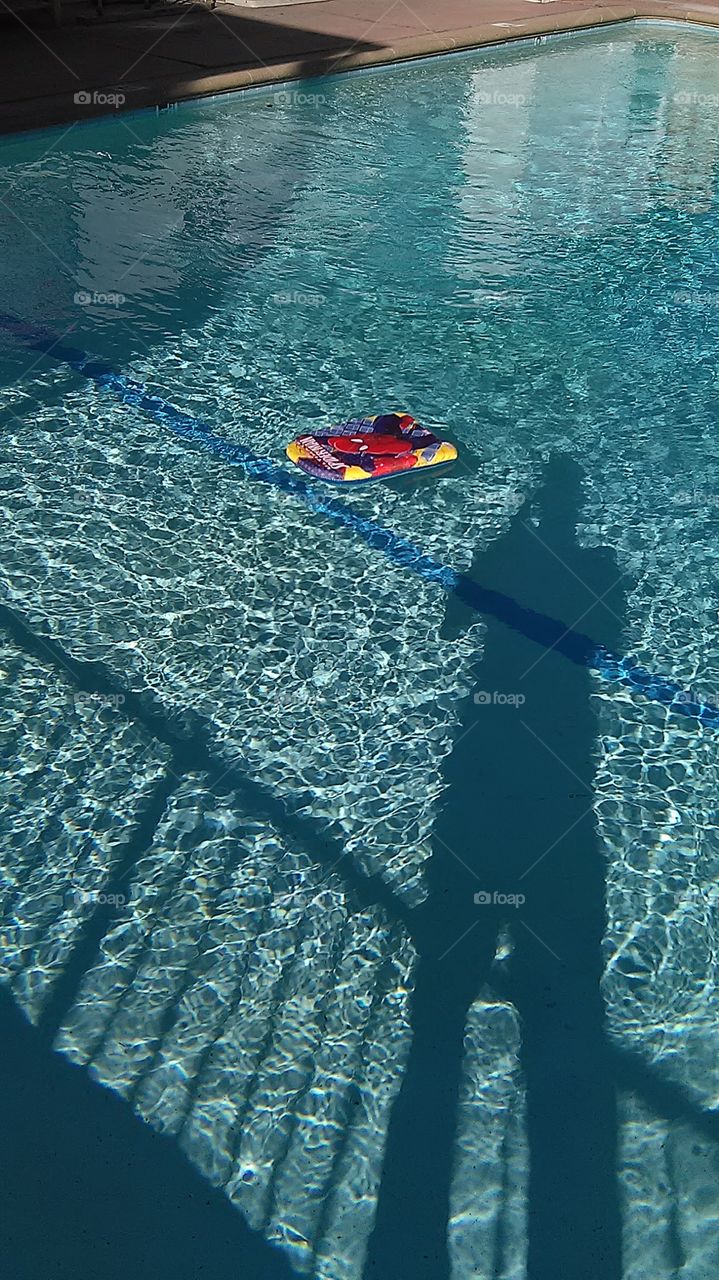 Floating shadow. Early morning poolside