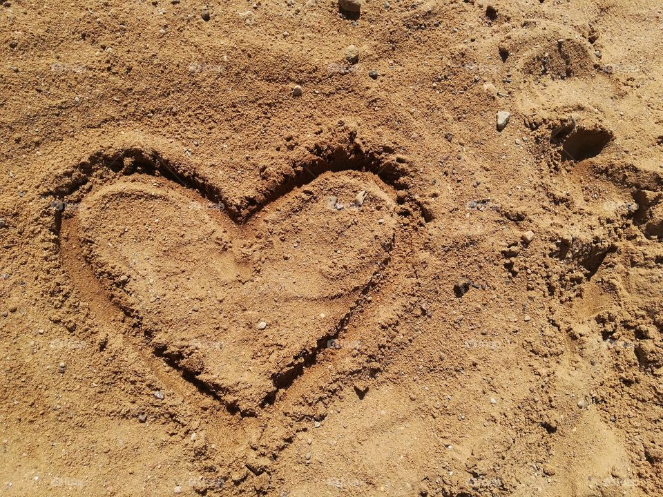 heart drawn in the sand; sign of a heart on the sand; summer, background, close-up; heart sign, heart-shaped