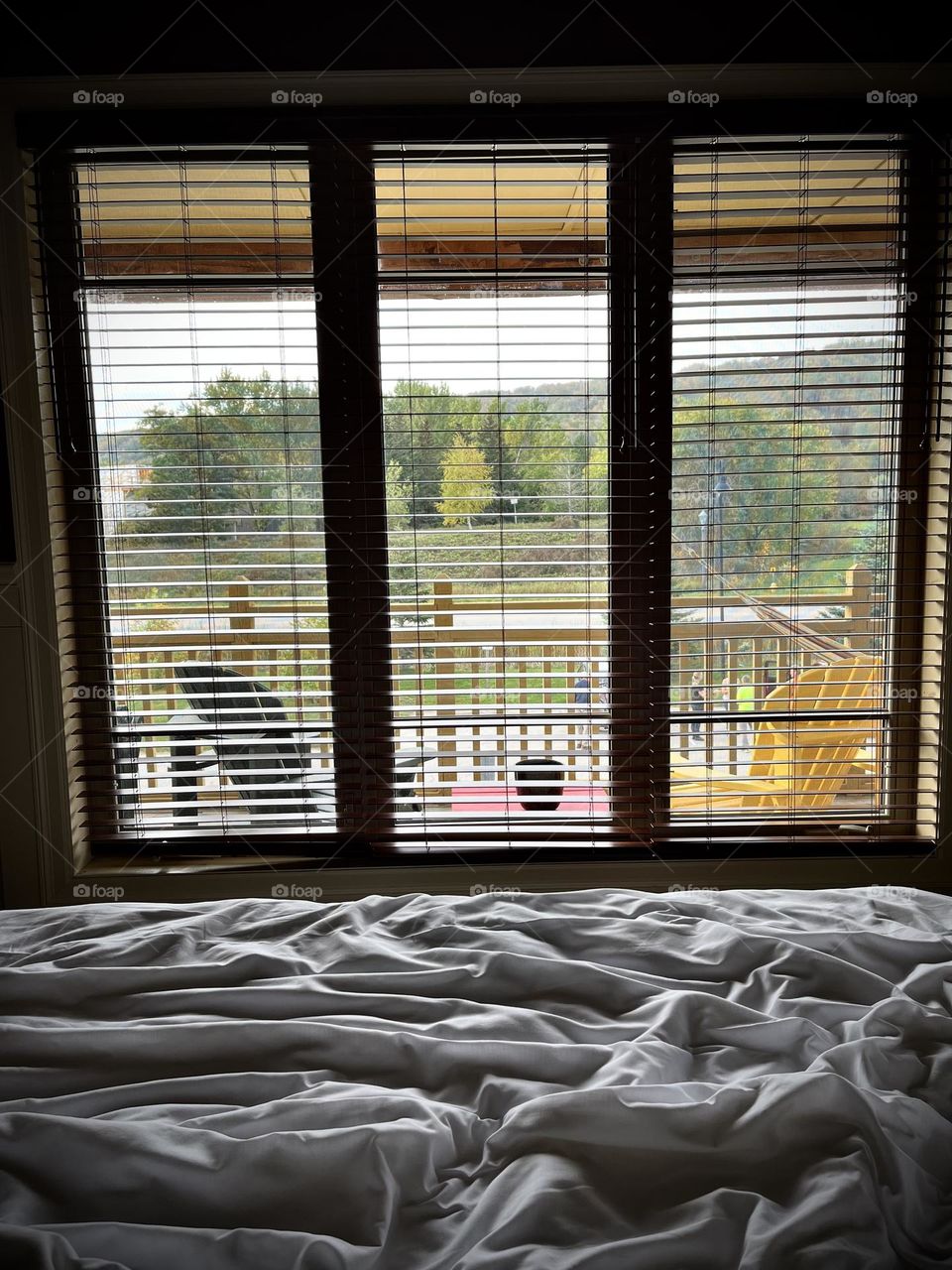 Window view from bed , three big rectangles and many in blinds , window view balcony with muskoka chairs looking towards blue mountains Collingwood 