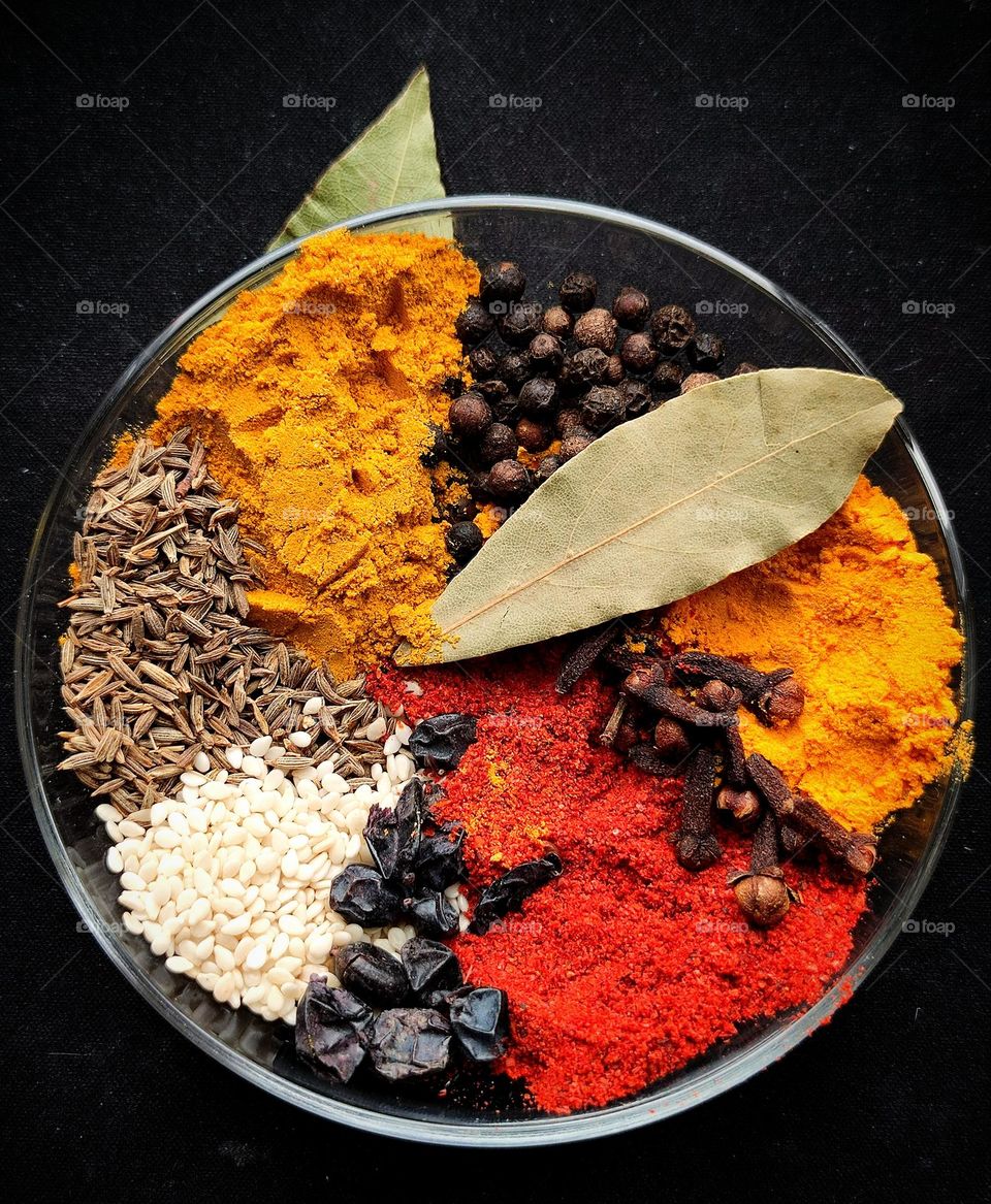 Spice flower fountain. Red paprika, yellow turmeric, dark yellow curry, black peppercorns, black barberry seeds, white sesame seeds, brown cumin seeds and green bay leaves