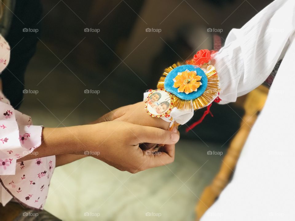 Sister tying raksha bandan to brother on rakhi day in India .holding  two hands .