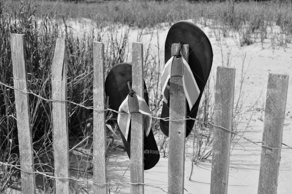 Flip-flops. Black-and-white image of flip-flops on a beach fence