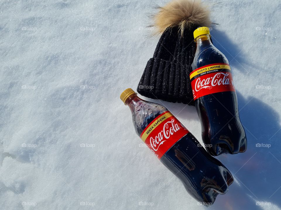 wool hat and bottles of Coca Cola resting on the snow