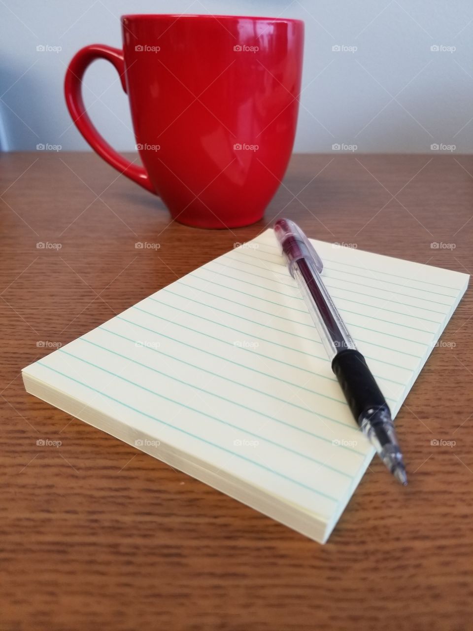 Ready to take notes. Red coffee cup with notpad and pen