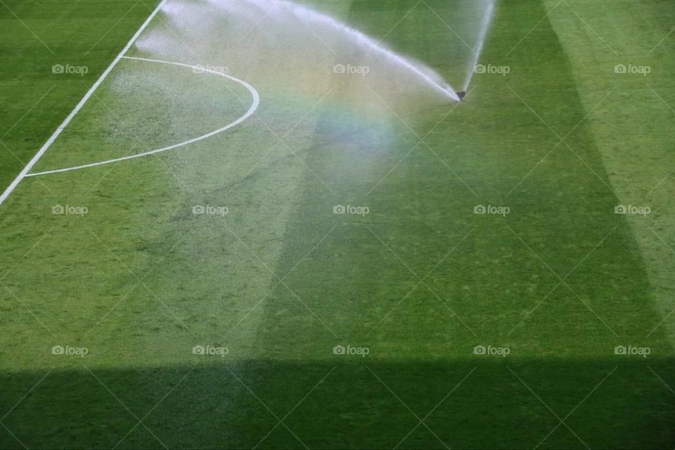 A rainbow on a watered soccer field