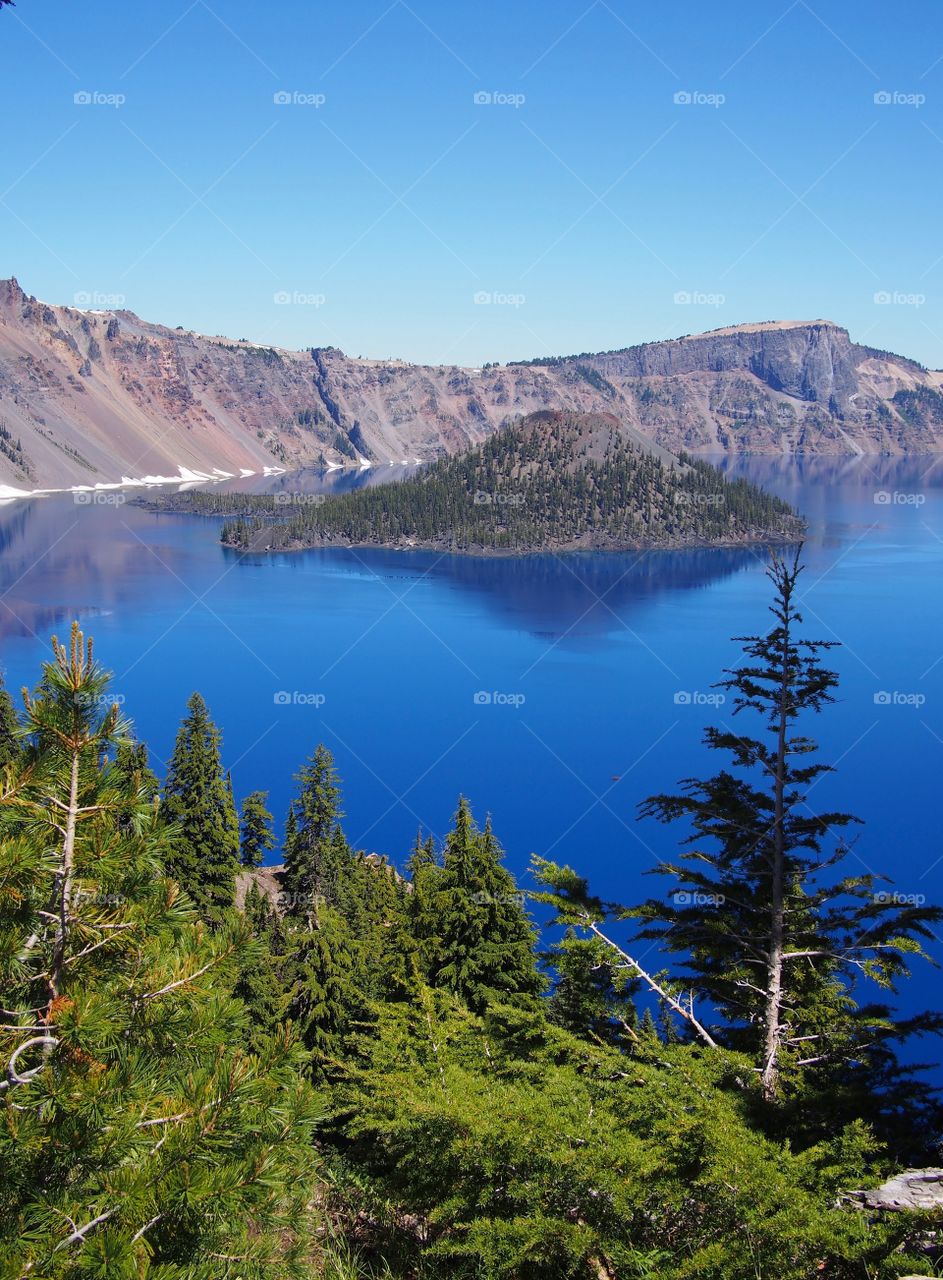 Wizard Island reflecting in the rich blue waters of Crater Lake in the forests of Southern Oregon on a sunny summer morning. 