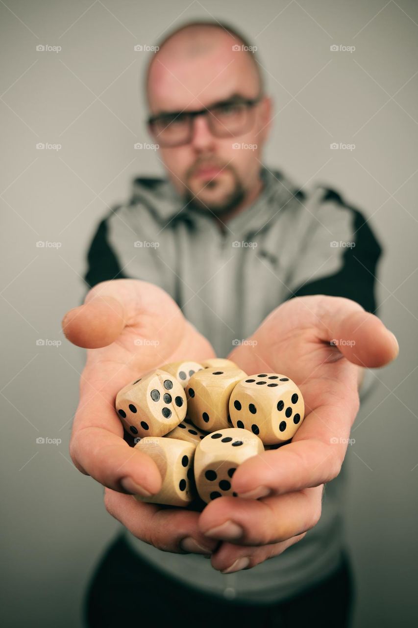 Man holding wooden dice with numbers in front of himself