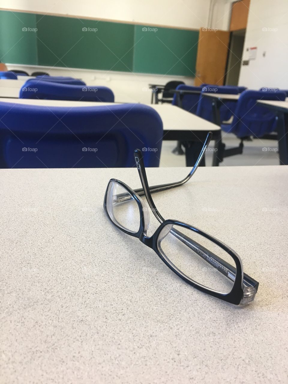 Glasses on a desk in an empty classroom