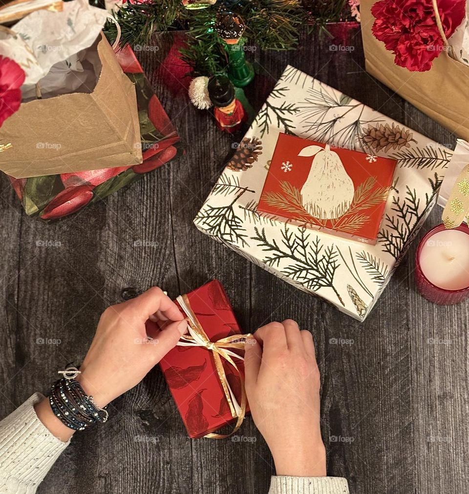 Hands in frame, wrapping gift, top down view, red wrapping paper