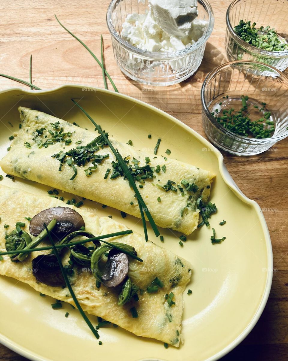 Sunny yellow omelette with garden herbs on a sunny yellow plate enhanced by the light from a sunny kitchen window