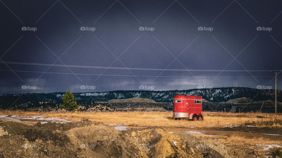 Lonely red trailer and the mountainous plains.