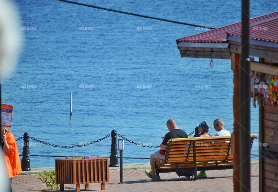 several people on a bench by the sea