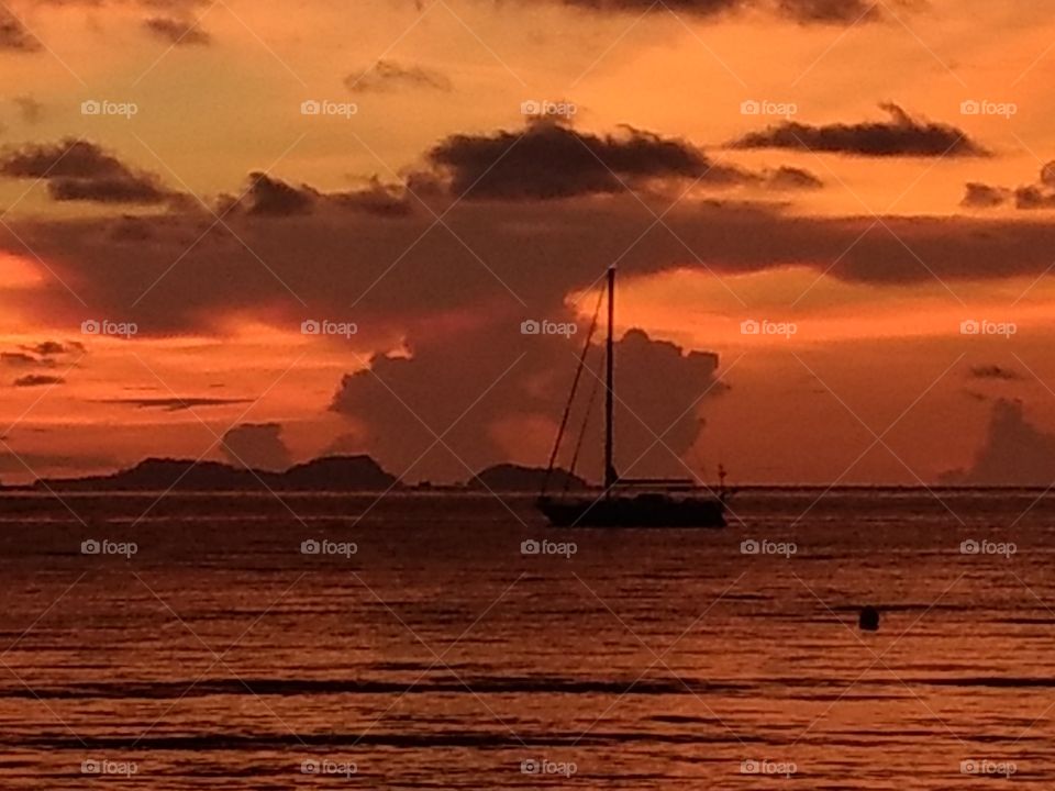 Dramatic sunset with sailboat at anchor, dark brilliant orange , Malaysia, Asia, sea, boat, sillouette, storm clouds