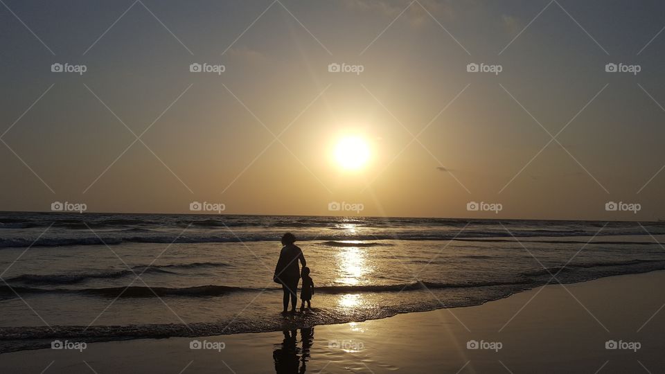 Little baby enjoying sunset with Mother in beach