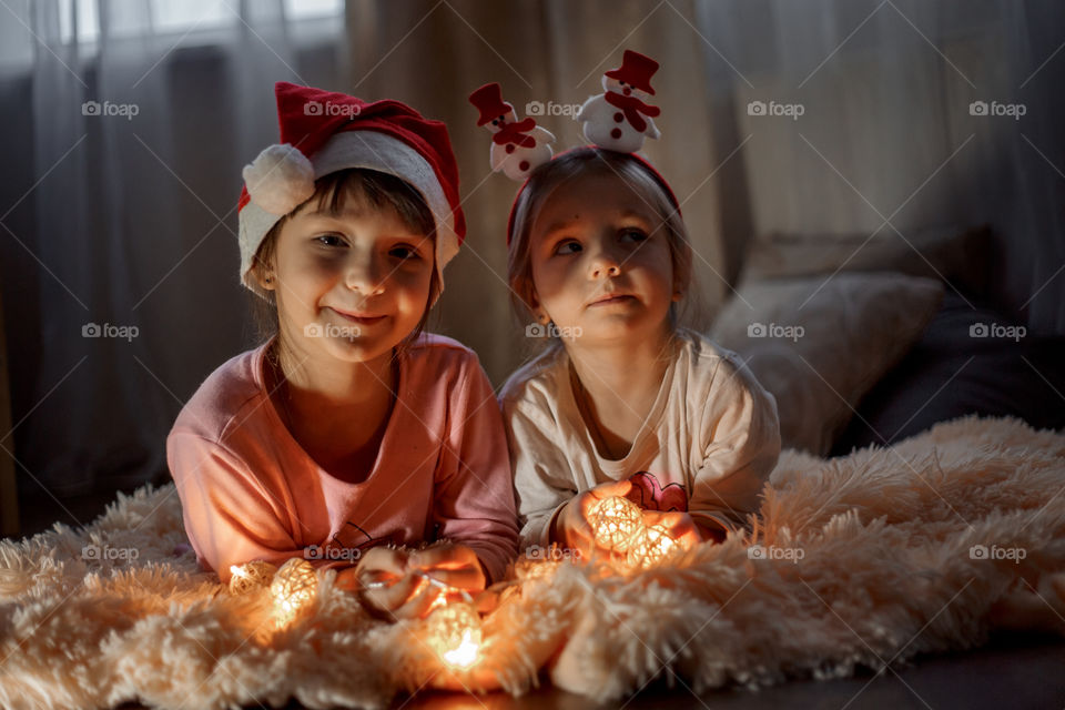 Little sisters reading a book at Christmas time 