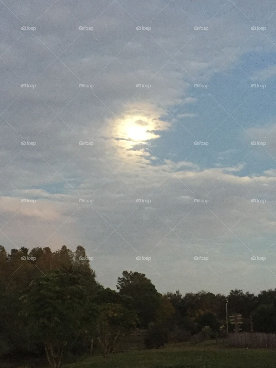 Early evening gigantic moon partly cloudy