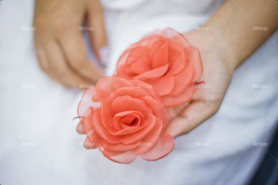 Closeup on a hand holding a Hair accessory made with Tissue flowers and salmon color