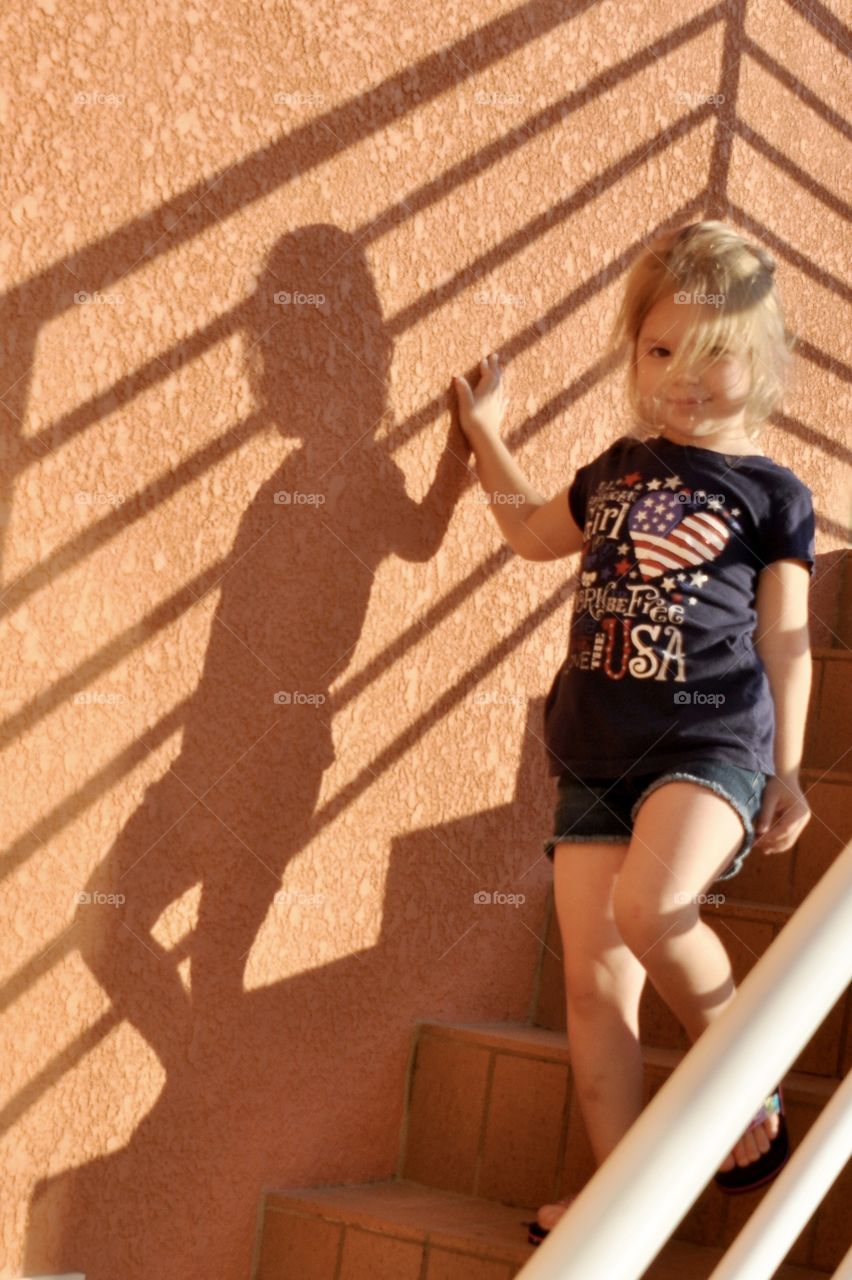 Little girl going down the stairs with her shadow on the wall