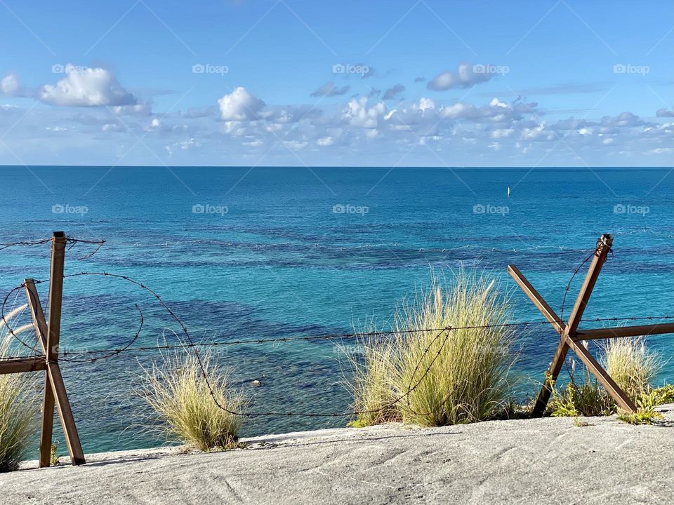 A barbed wire fence separating a fort from the Atlantic Ocean 